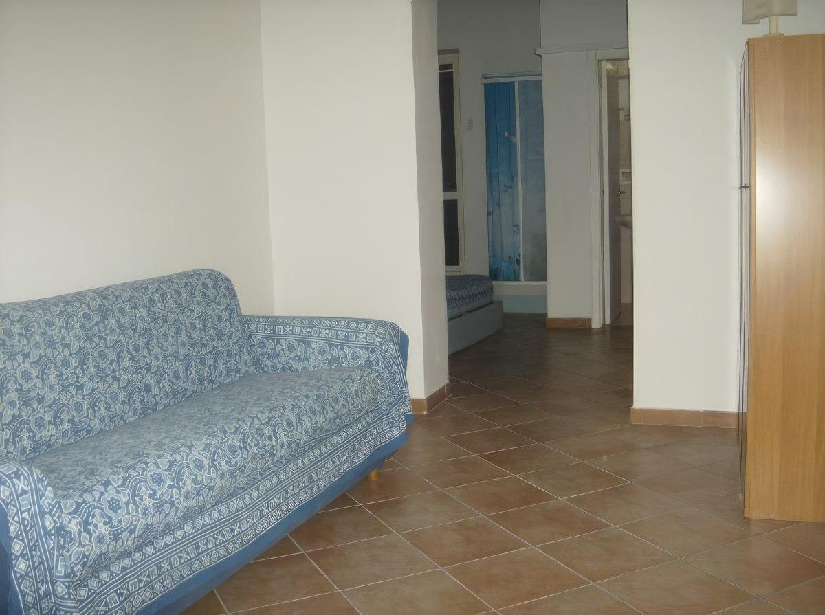 sala con divano letto matrimoniale e TV. Sullo sfondo si vede la doccia in camera