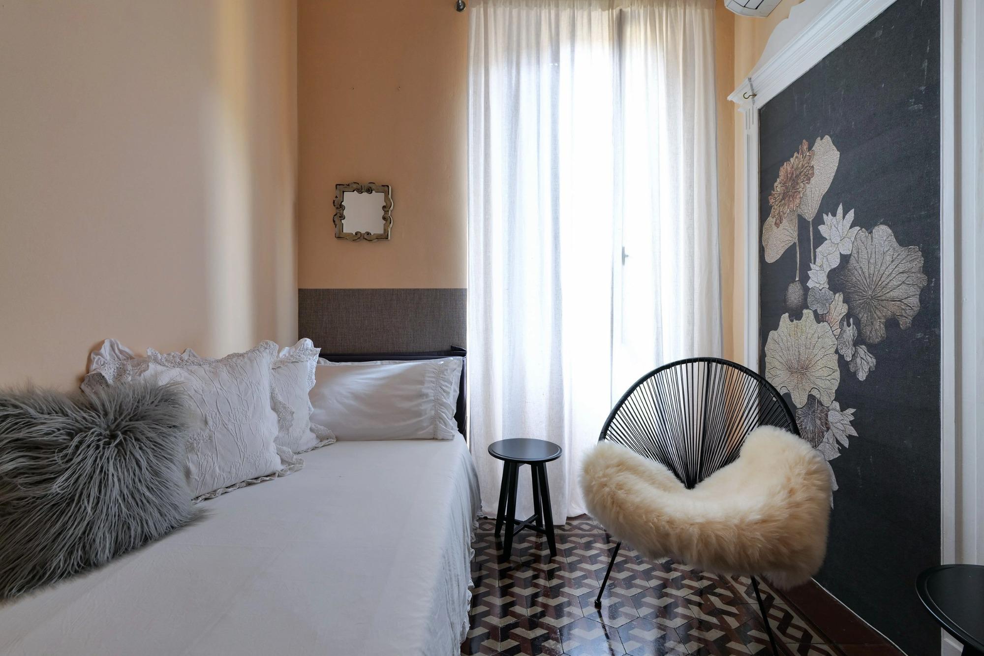 Single Superior Room di House of Frames Milano con pavimento originale in cementine e poltrona Acapulco