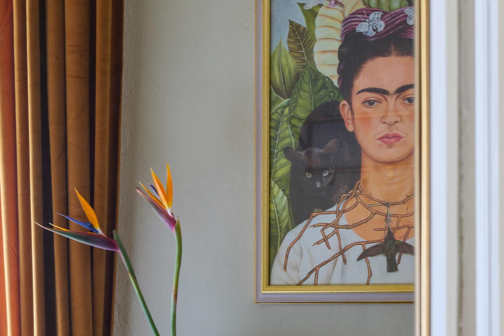 Dettaglio della Double Deluxe Room di House of Frames Milano con ritratto di Frida Kahlo e fiori Strelitzia