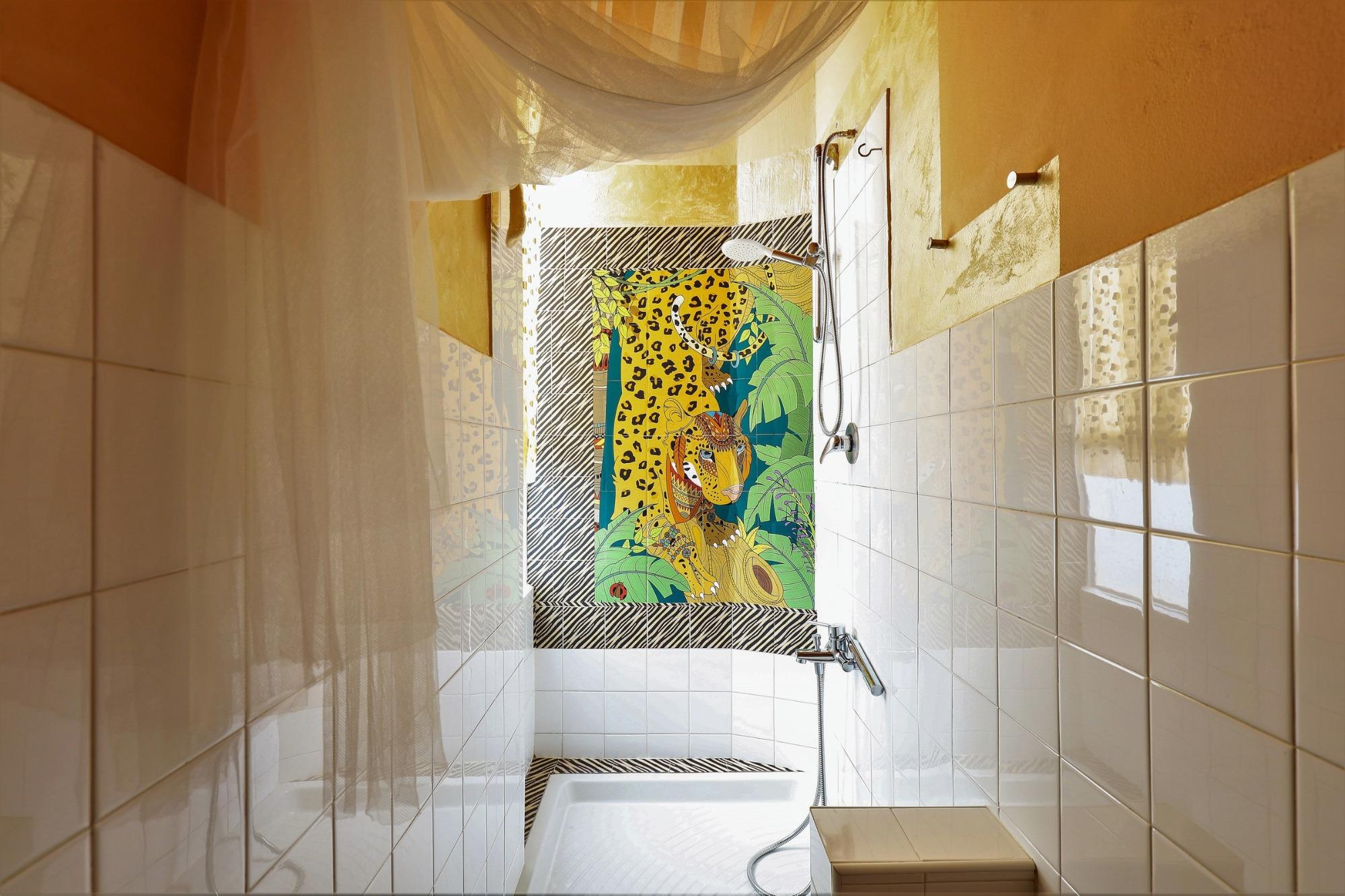 Doccia del bagno condiviso di House of Frames Milano con dettagli animalier e decorazione tropicale