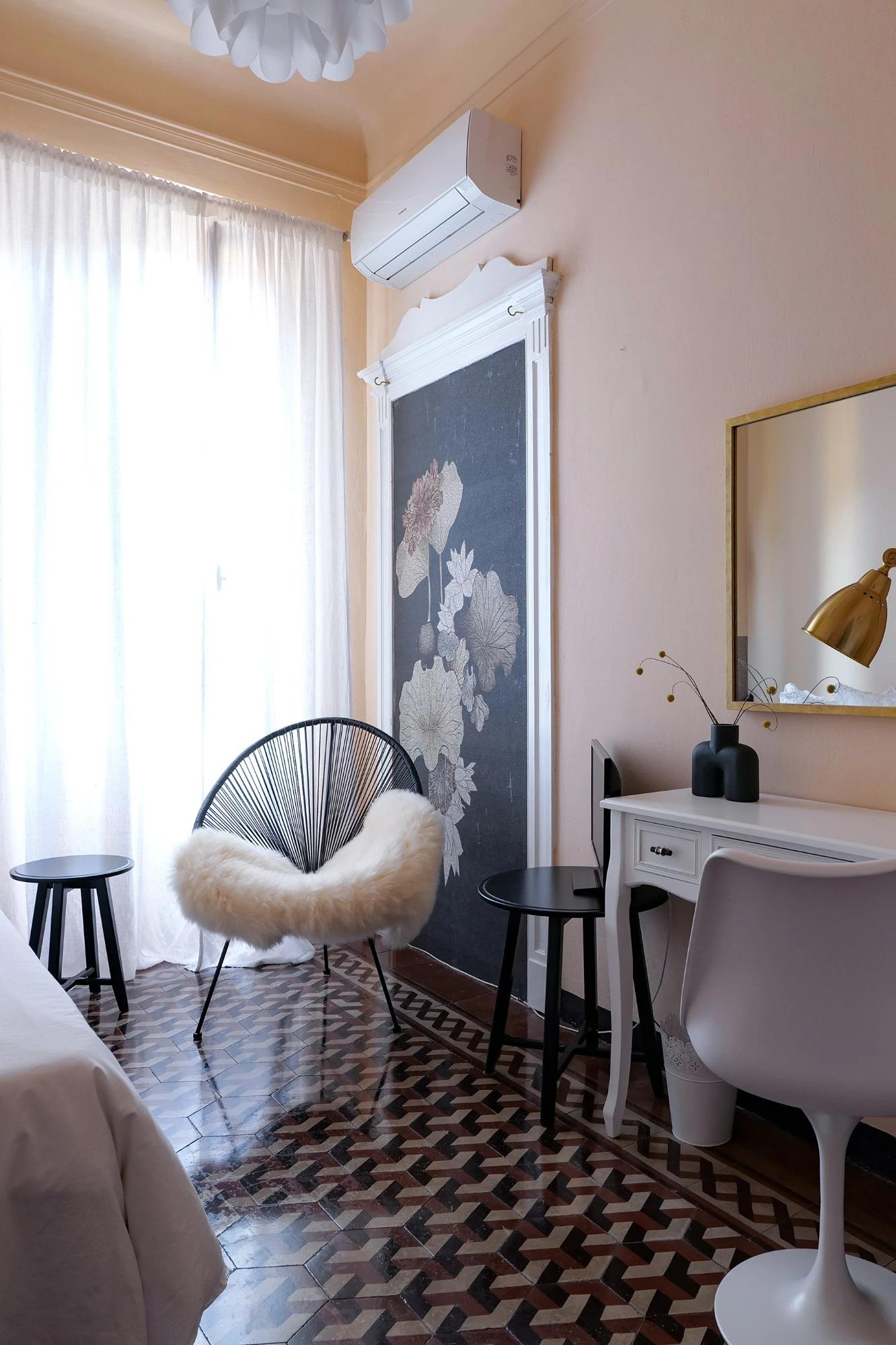 Camera singola di House of Frames Milano con cuscini decorativi e poltrona Acapulco.