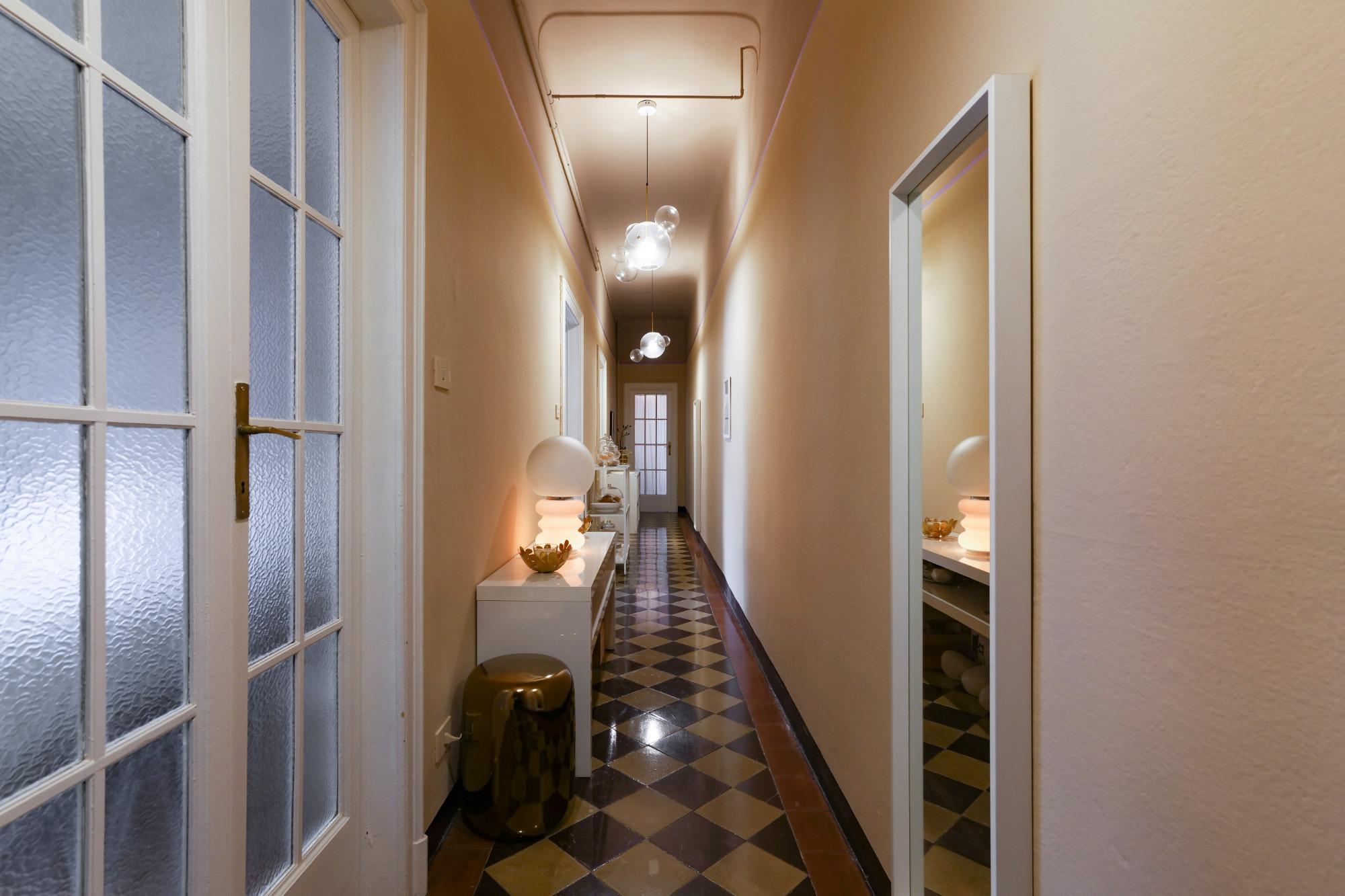 Corridoio appena fuori dalla camera singola di House of Frames Milano, con pavimento originale in cementine e lampada Bolle di Giopato & Coombes.