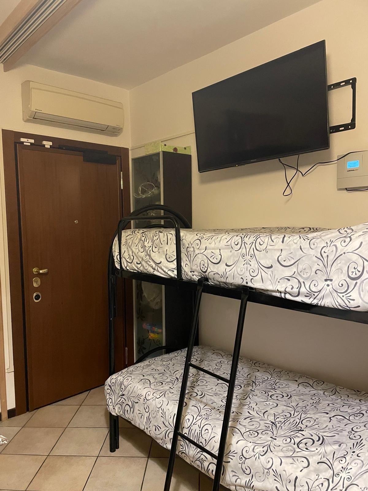 letto a castello di fronte alla zona giorno in fondo si vede la porta di entrata principale