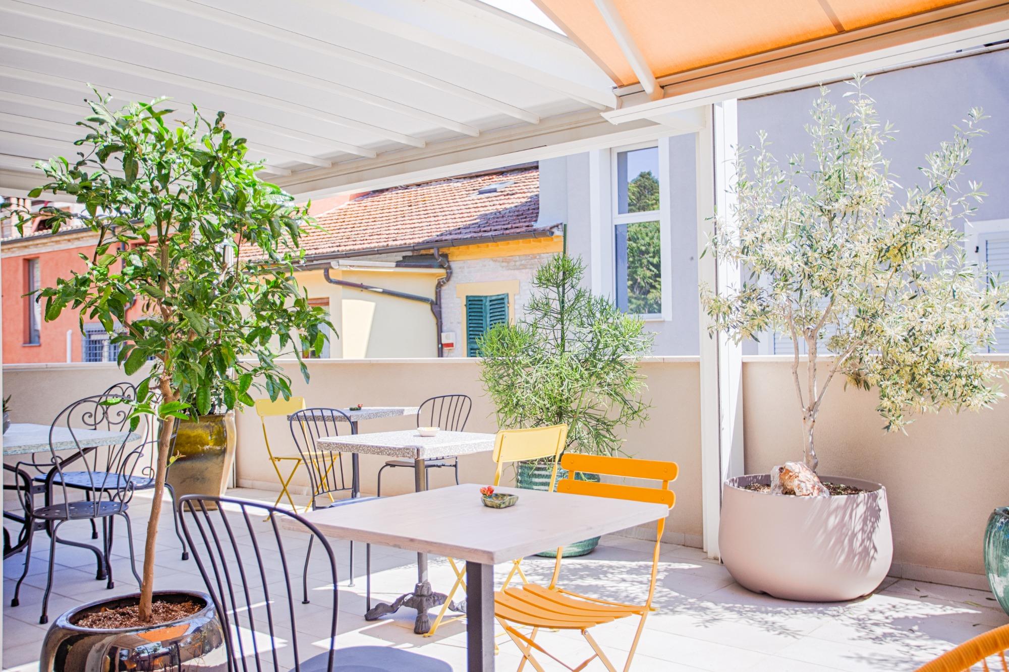 Grande terrazza esterna coperta del B&B Fontanella 32 a Porto Sant'Elpidio attrezzata con tavoli, sedie colorate e piante per la colazione all'aperto