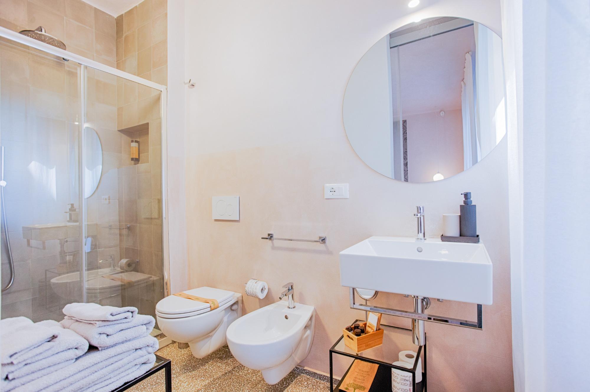 Bagno privato della Camera Sabbia del B&B Fontanella 32 con doccia moderna nei toni del beige e specchio tondo
