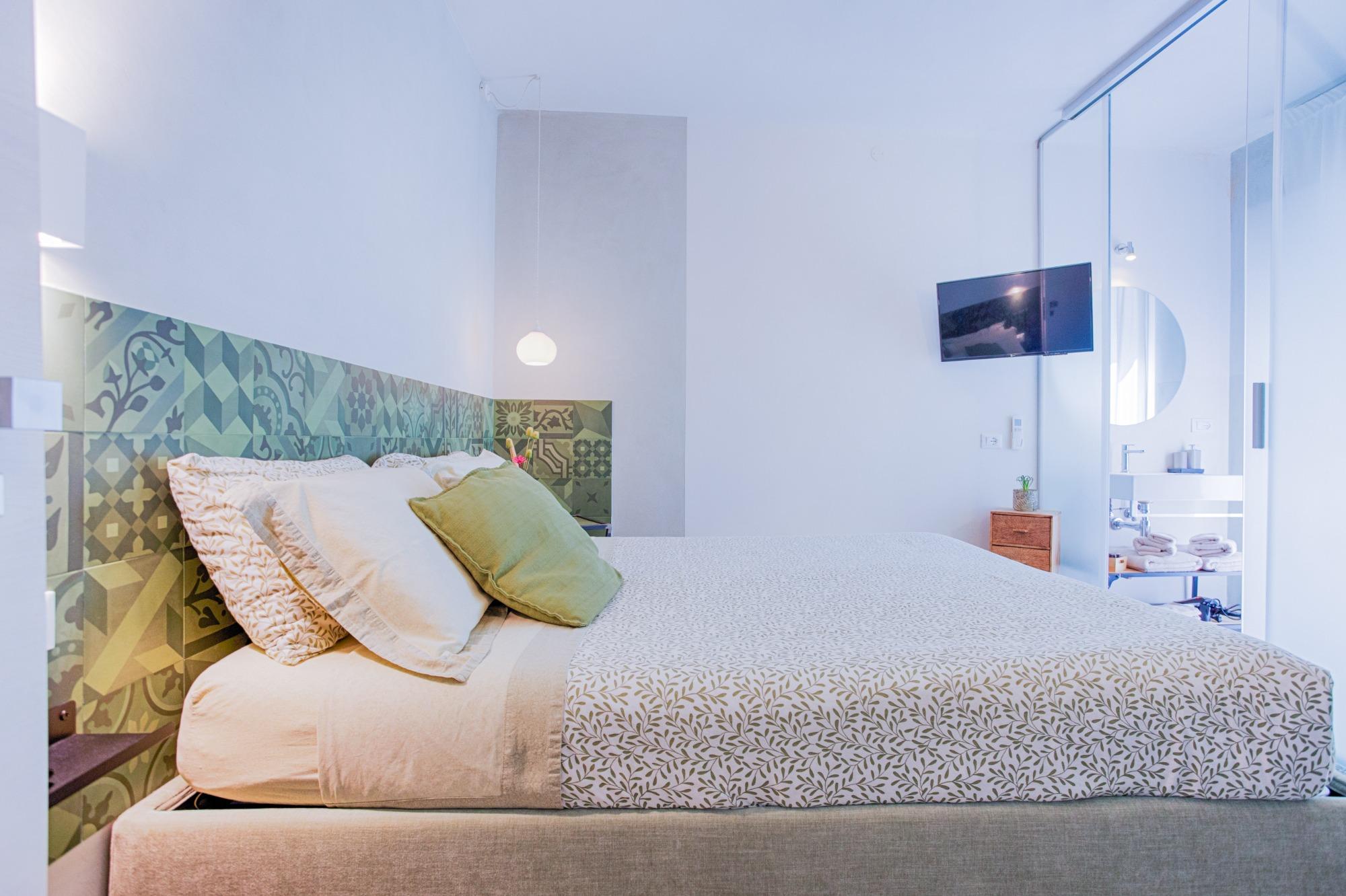 Letto matrimoniale della Camera Verde del B&B Fontanella 32 con testata geometrica verde e smart TV a parete.