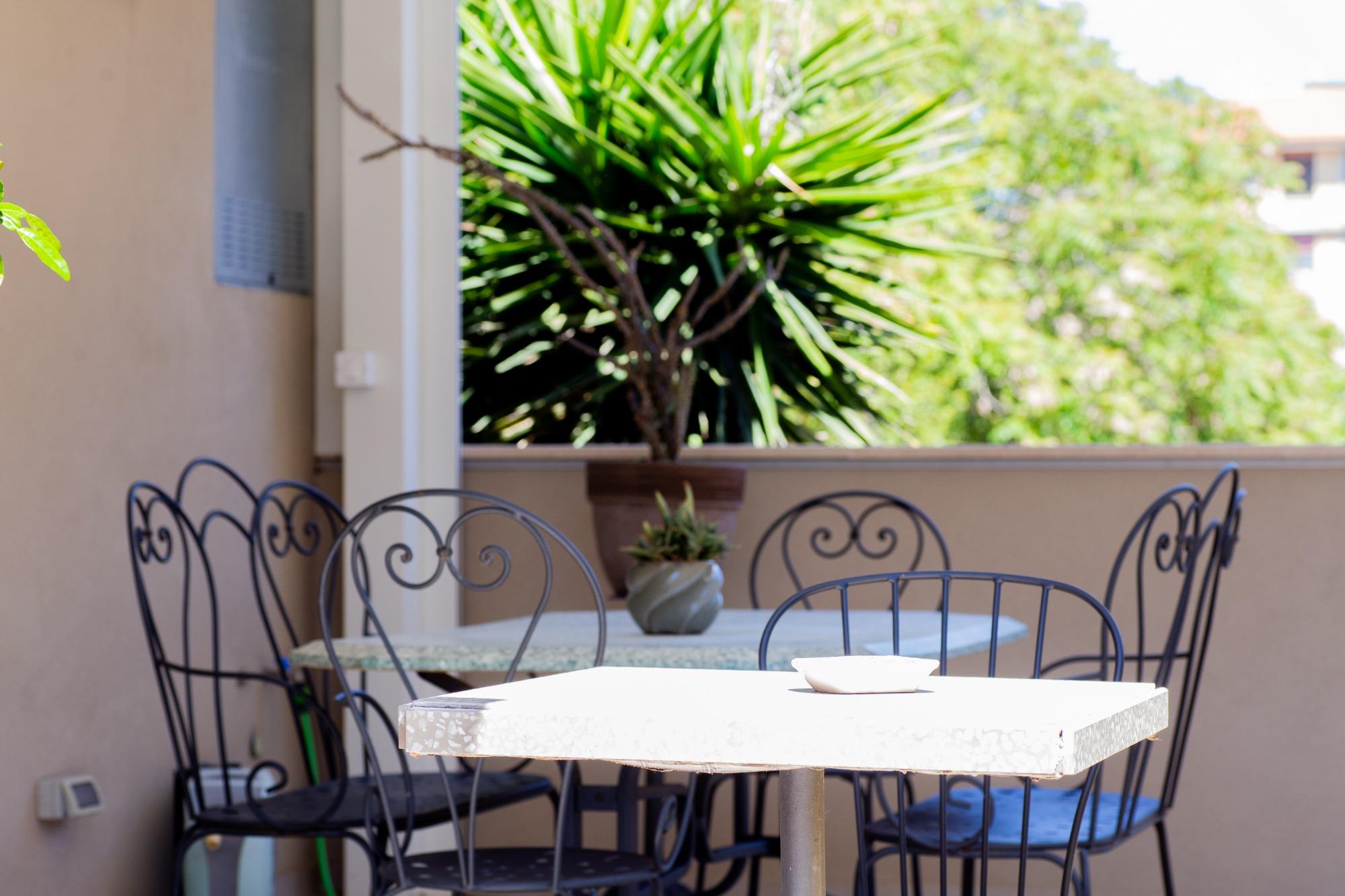 Tavoli all'aperto e sedie in ferro battuto sul terrazzo del B&B Fontanella 32 a Porto Sant'Elpidio, circondati da piante verdi per il relax degli ospi