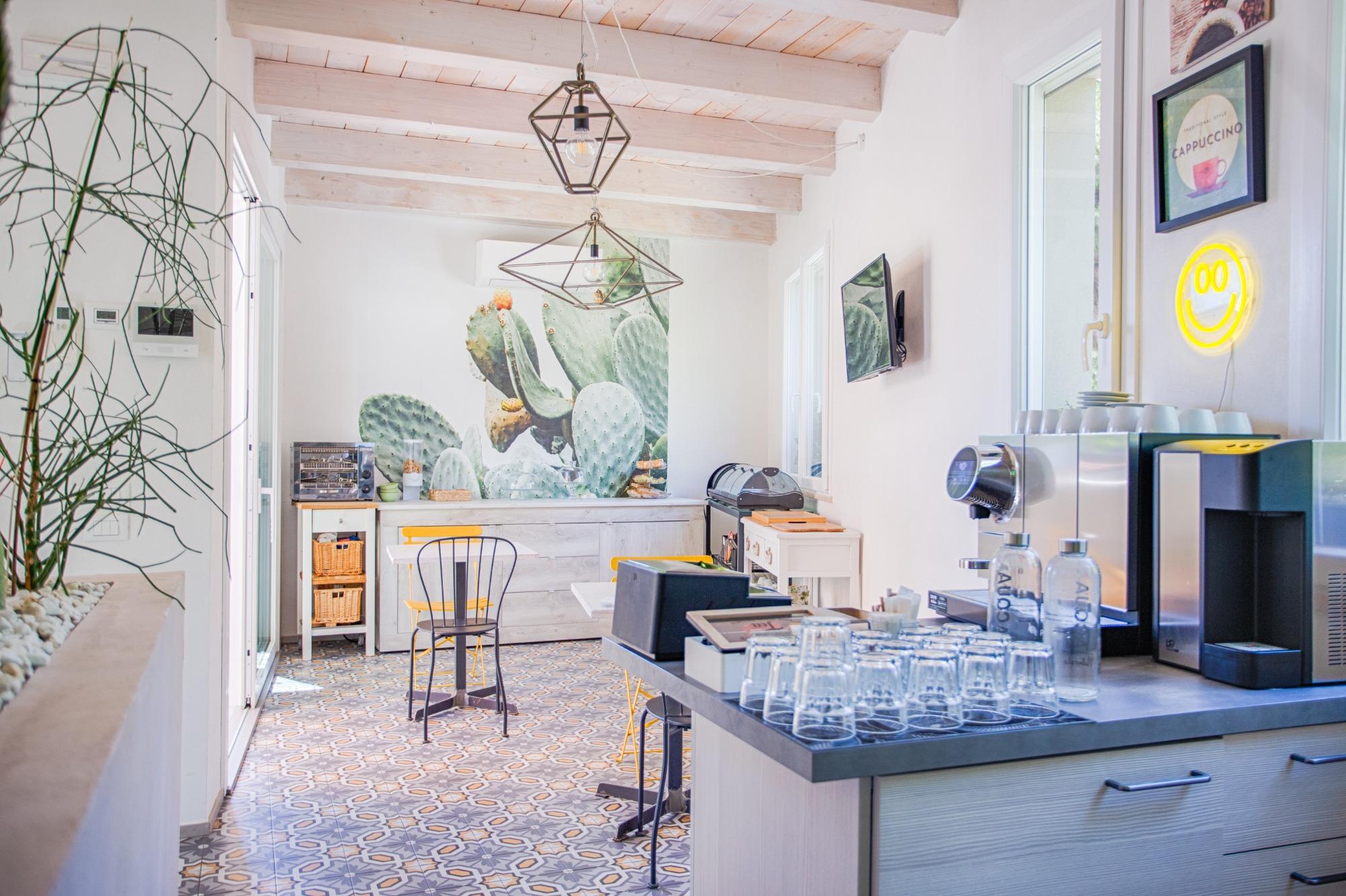 Angolo bar con macchina del caffè professionale e sala colazioni del B&B Fontanella 32 a Porto Sant'Elpidio, caratterizzata da arredi moderni e travi