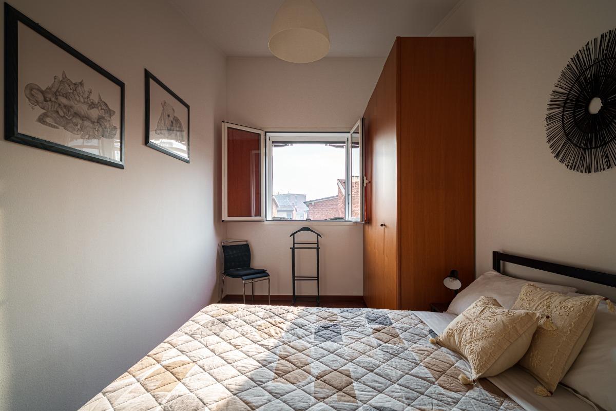 Camera da letto finestrata con letto matrimoniale e armadio