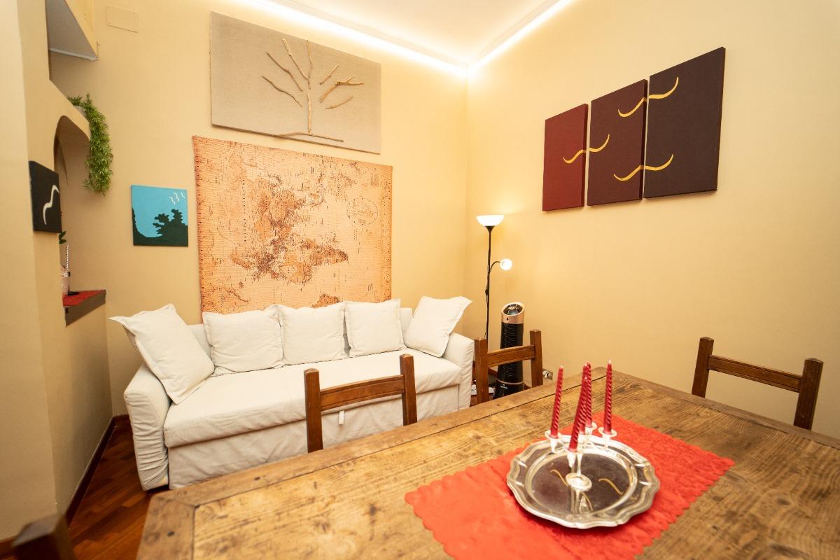 Salotto con divano letto. Dipinti etnici. Un grande tavolo di legno dove è possibile accendere candele romantiche.