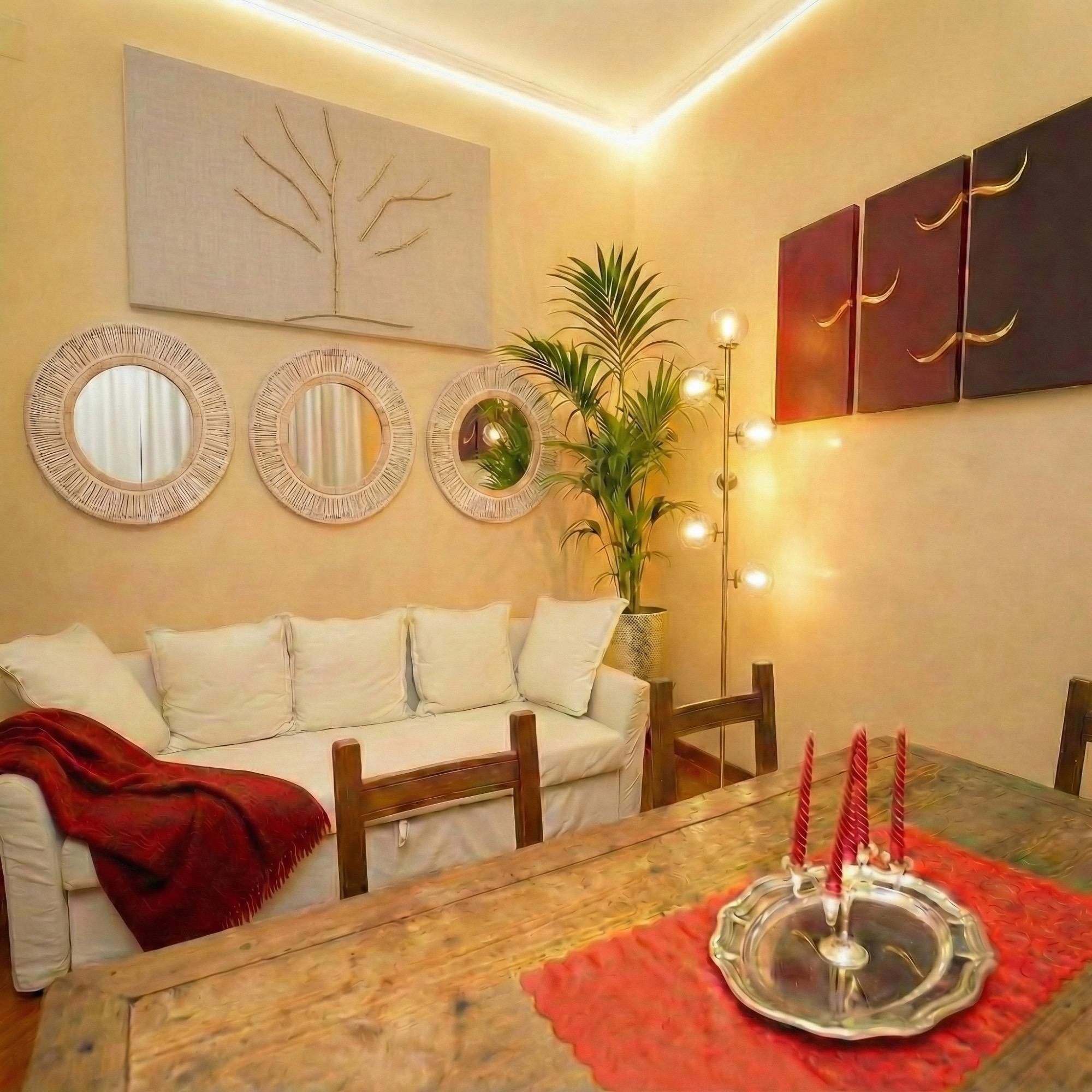 Salotto con divano letto. Dipinti e specchi etnici. Un grande tavolo di legno dove è possibile accendere candele romantiche.