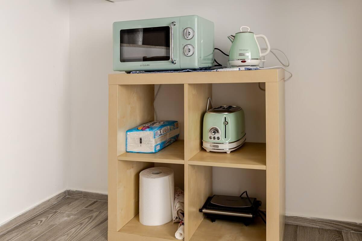 Cucina accessoriata con forno, macchina del caffè e utensileria varia.