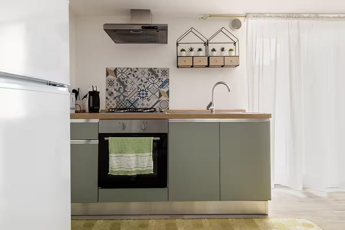 Cucina accessoriata con forno, macchina del caffè e utensileria varia.