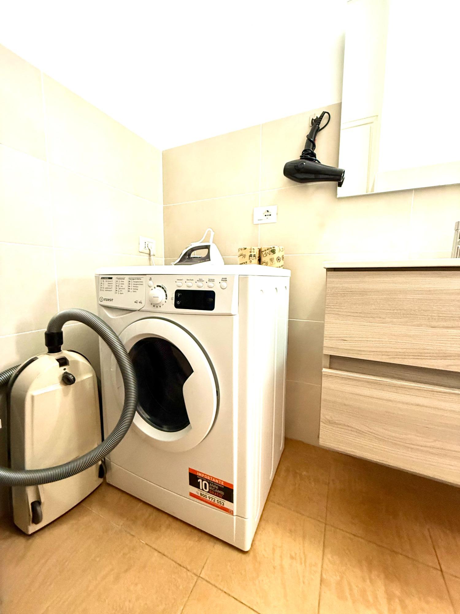 Questo spazio include una lavatrice, un aspirapolvere, un ferro da stiro e un asciugacapelli, offrendo tutto il necessario per un soggiorno confortevo