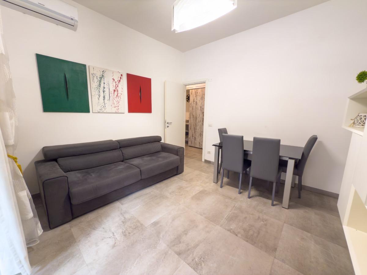 Soggiorno con divano letto matrimoniale, aria condizionata, tavolo da pranzo, tv a schermo piatto, accesso al giardino.