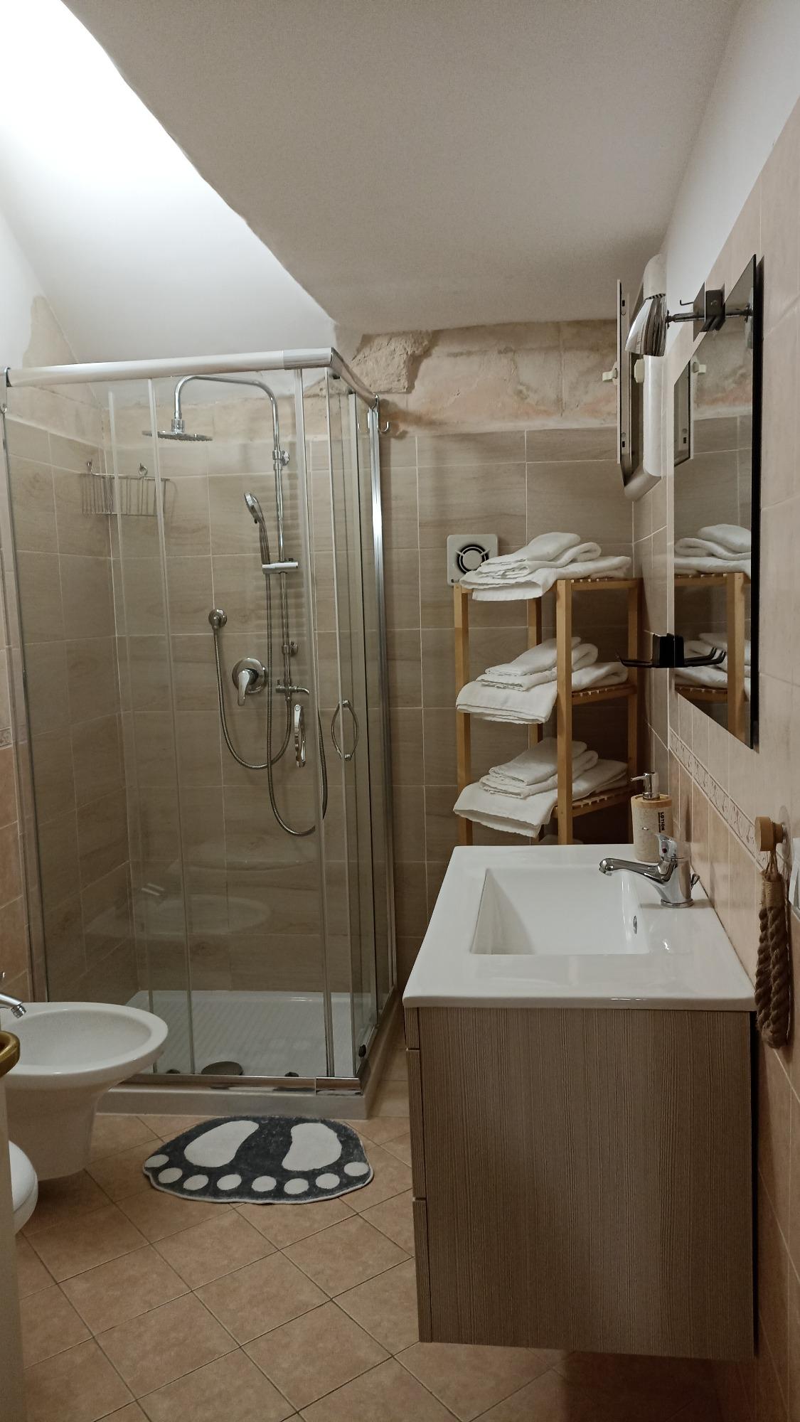 Bagno comodo, con termosifone, lavabo, e box doccia.