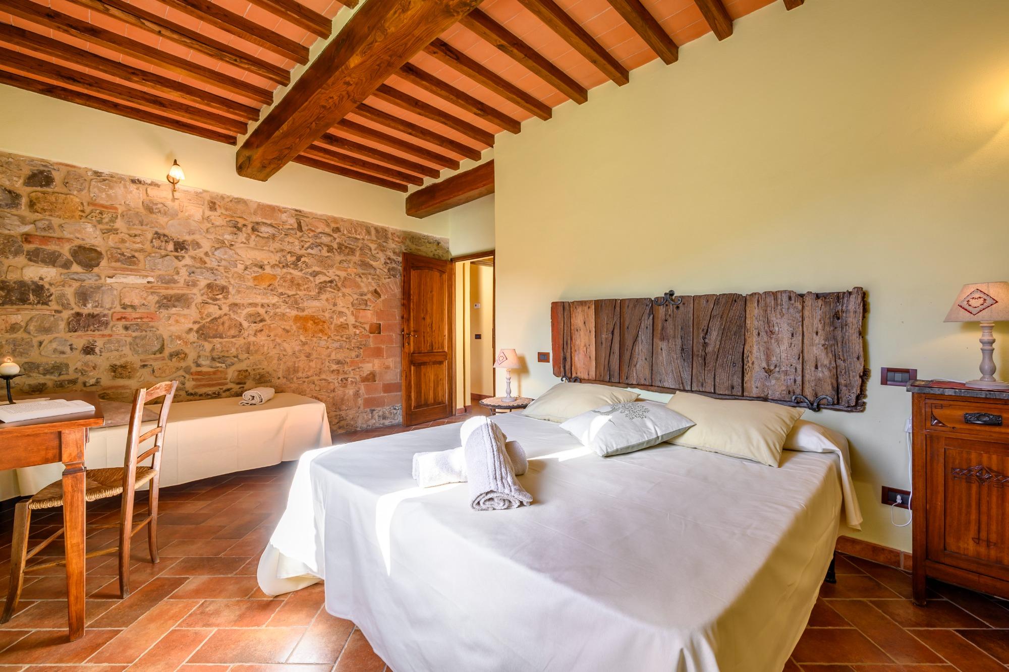 Camera matrimoniale con travi a vista e testiera con porta origine della Landuccia