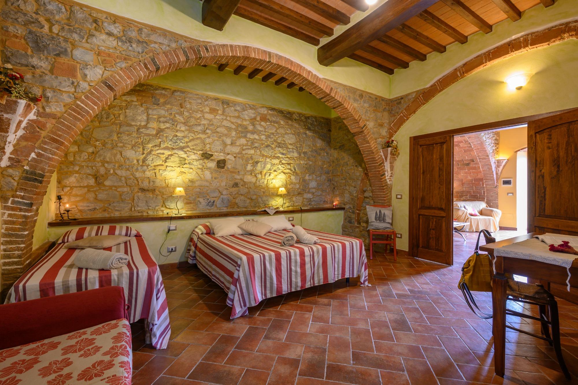Camera spaziosa con archi in mattoni e pareti in pietra