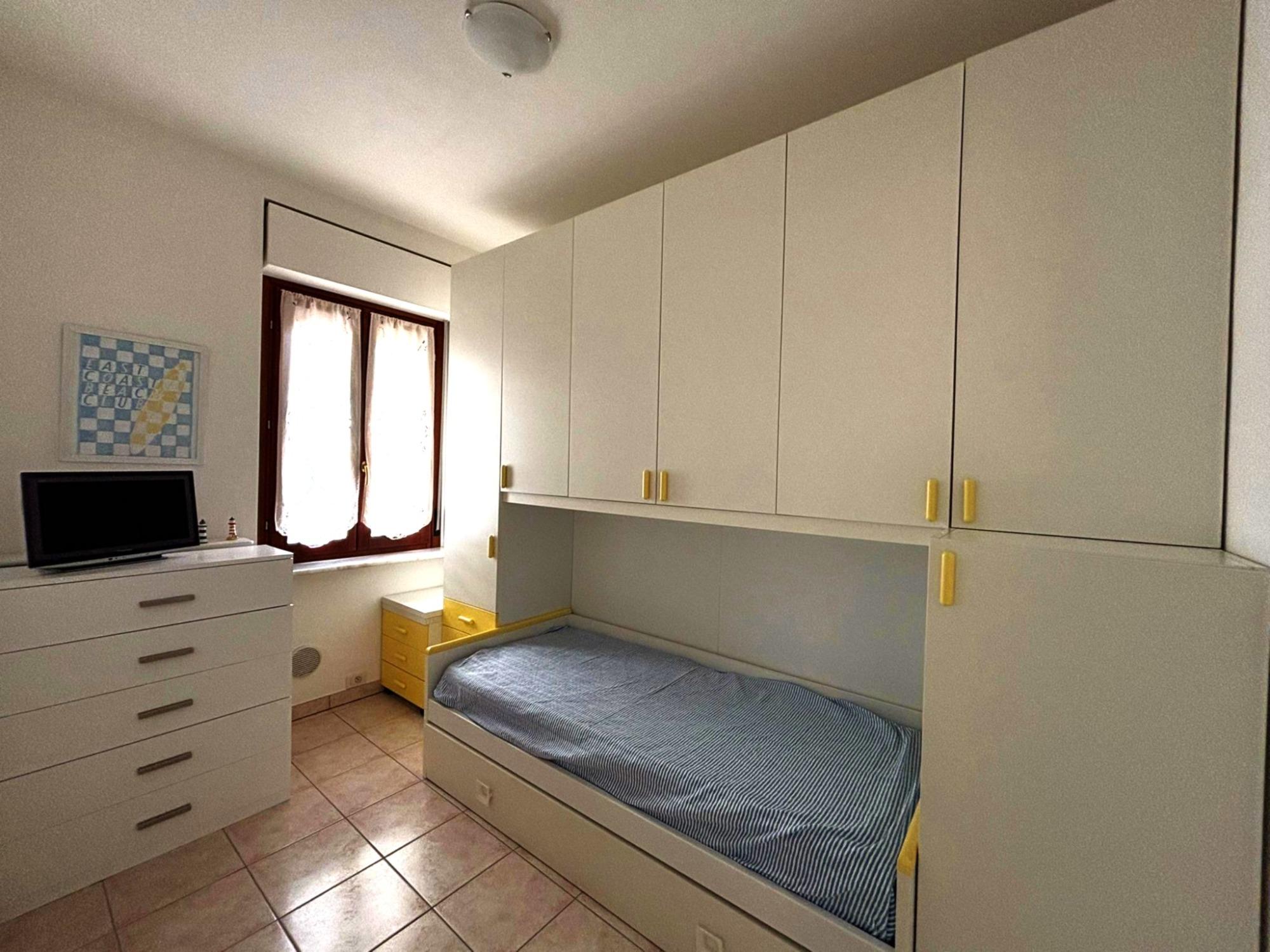 cameretta con secondo letto estraibile, televisore e ampia armadiatura