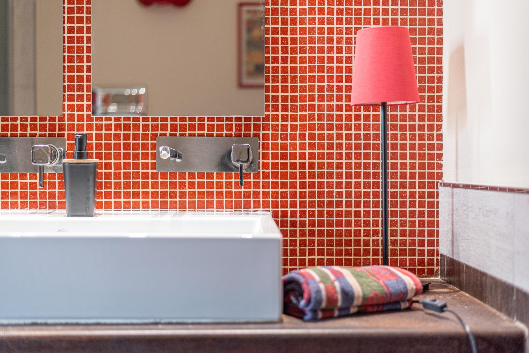 Armonia cromatica: il vivace mosaico rosso incontra dettagli coordinati e luci soffuse. Ogni particolare a Sunny Suite è scelto per creare un’atmosfer