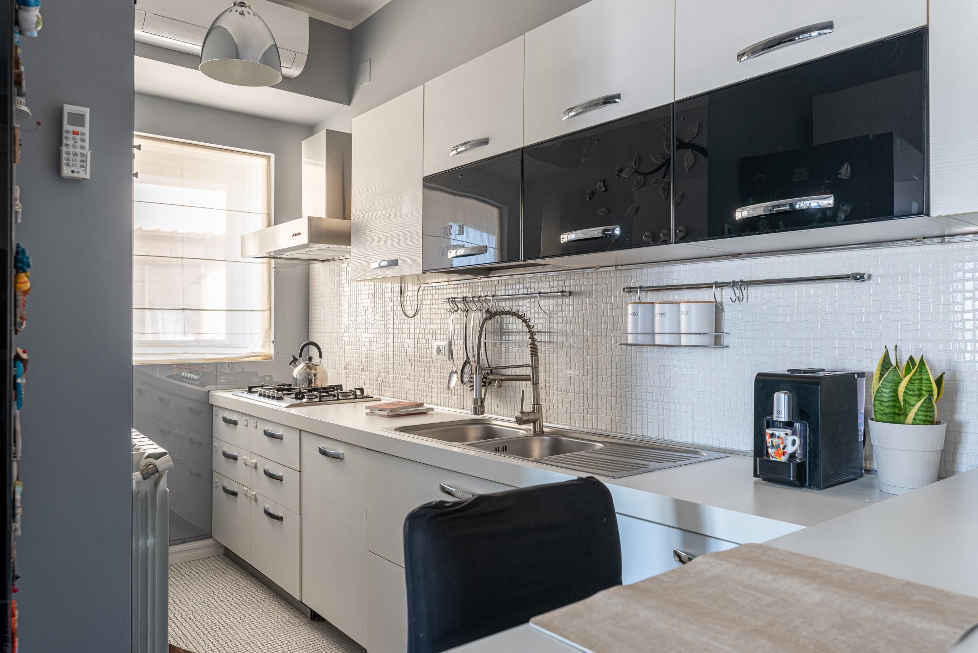 Stile minimal ed elegante: cucina in laminato bianco con raffinati elementi a specchio neri. Un design moderno e pulito per cucinare con classe a Sunn