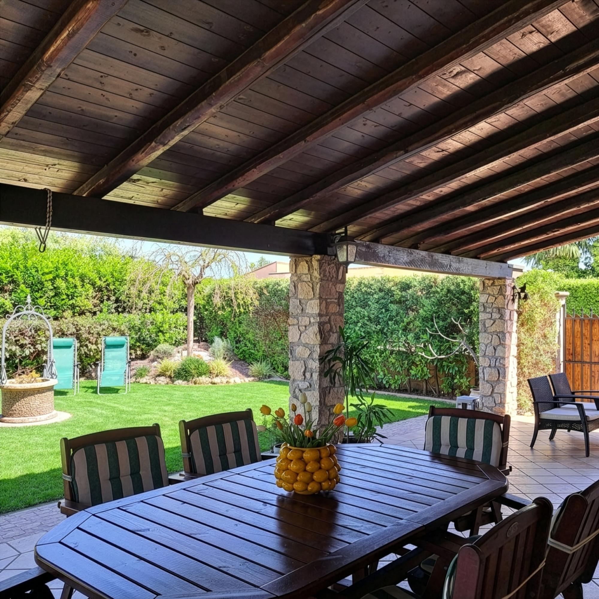Vista veranda con tavolo da pranzo e giardino con sedute