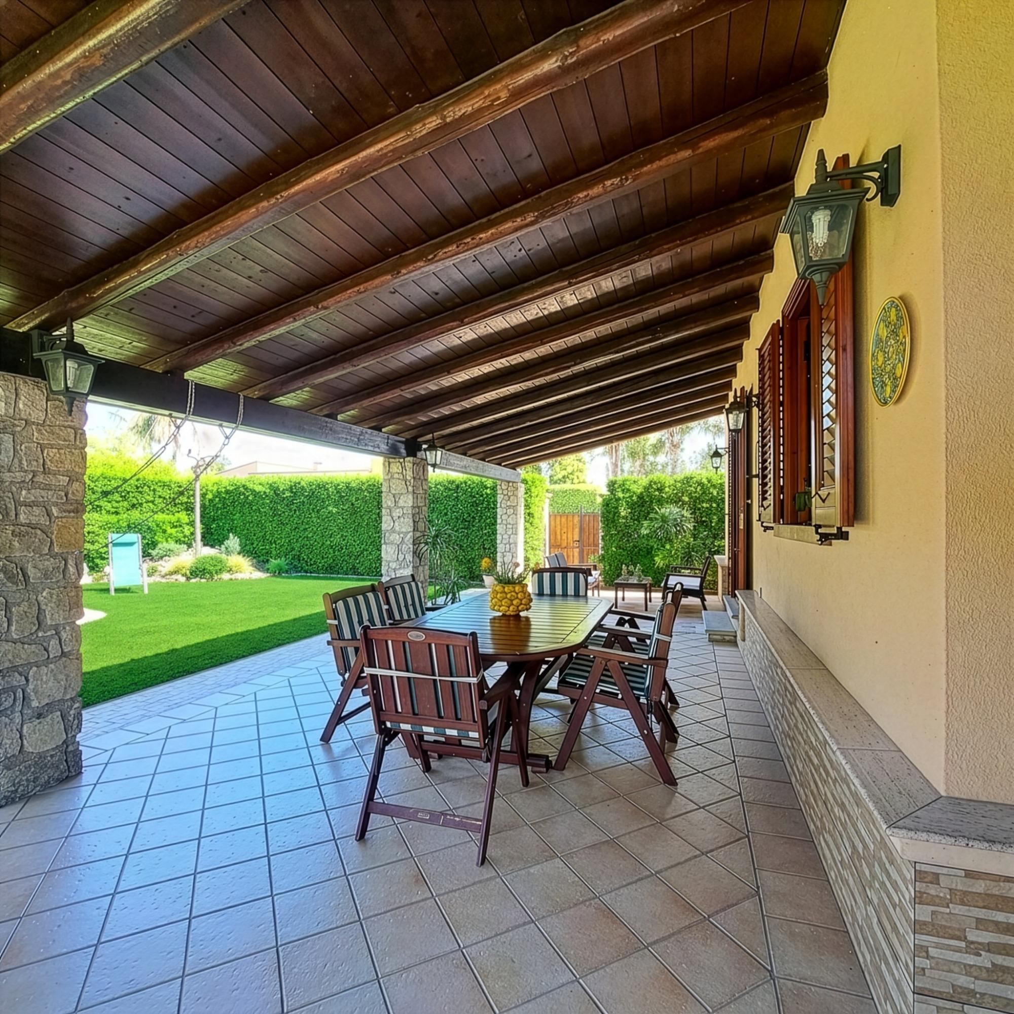 Vista veranda con tavolo da pranzo e giardino con sedute
